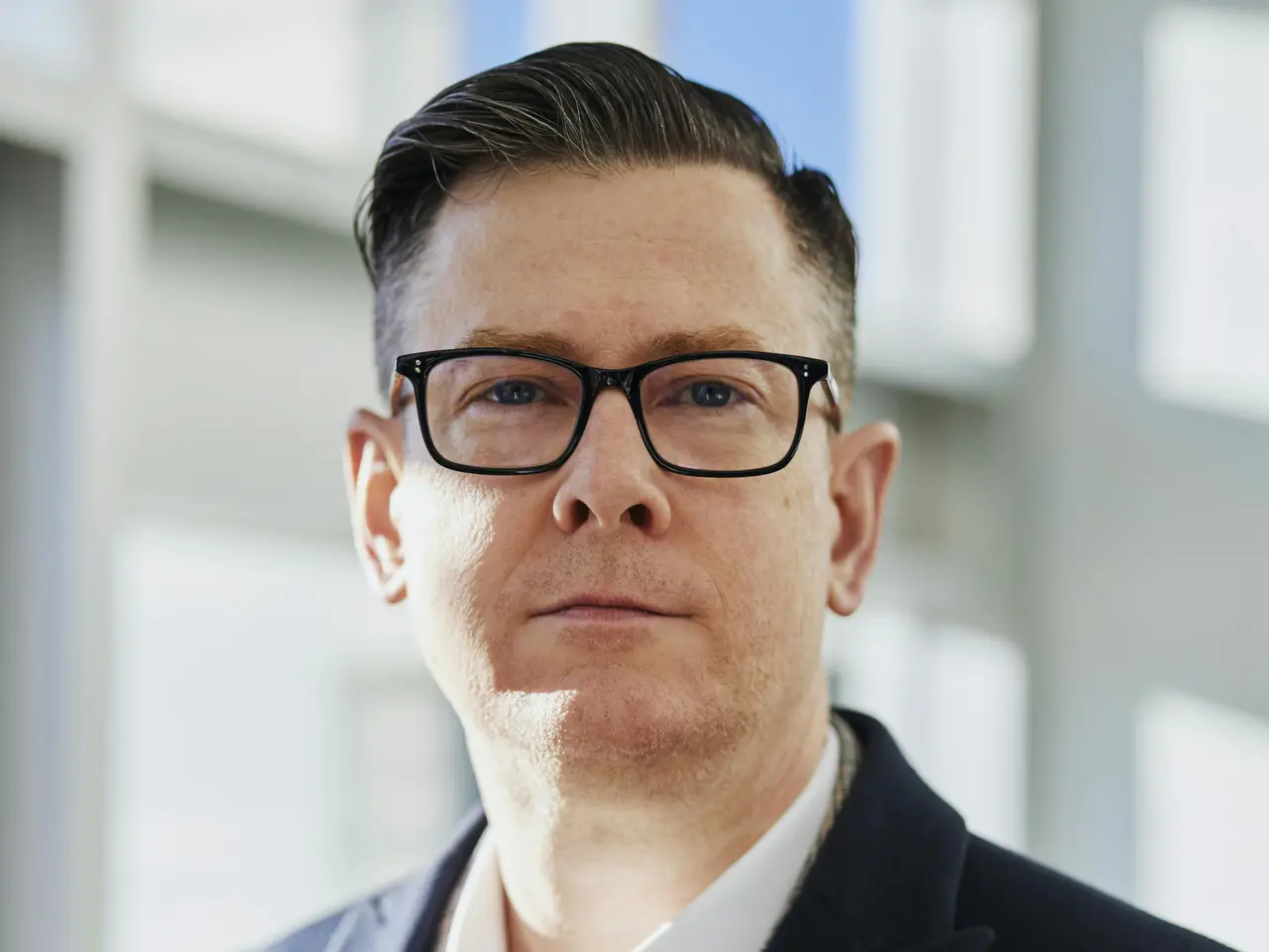 Mężczyzna w garniturze trzyma smartfon z otwartą aplikacją TikTok, symbolizując obecność CEO w mediach społecznościowych